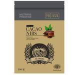 El Cacao Cacao Nibs drink in a glass, featuring dark chocolate-colored liquid with cacao nibs visible, served in a clear glass.