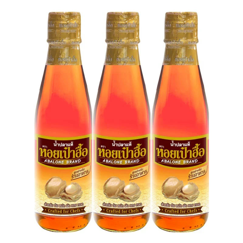 ABALONE Premium Fish Sauce 700 ml bottles, clear glass with dark liquid, label featuring fish imagery, on a kitchen countertop.