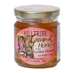 Jar of Hilltribe Gourmet Lychee Honey with a golden, sticky honey spread on a wooden surface, showcasing the product's rich texture.