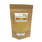Radiance Wholefoods Nutritional Yeast in a clear container, showing golden yellow flakes on a white background.