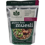 Brookfarm gluten free muesli with cranberries and macadamia nuts in a bowl on a wooden surface.