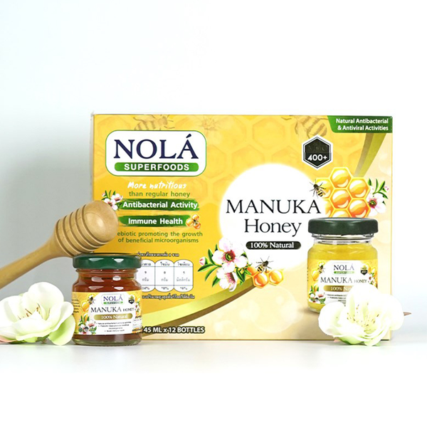 Bottle of Nola Manuka Honey Drink with honey and tea ingredients in a clear glass, showcasing the beverage's golden color.