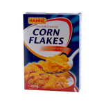 Hahne Corn Flakes in a cereal box, showing golden corn flakes with a bowl of cereal and milk on a breakfast table.