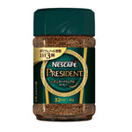 Nescafe President coffee drink in a clear glass with a frothy top, served hot with a coffee spoon on the side.