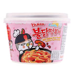 Spicy Samyang Buldak Topokki Carbonara instant noodles in a bowl with creamy sauce and garnished with green onions.