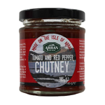 Jar of Arran Tomato and Red Pepper Chutney with fresh red peppers and ripe tomatoes on a wooden surface.