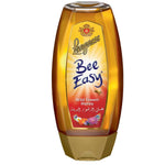 Jar of Langnese Bee Easy Bigenhoning honey with a golden color and honeycomb design on the label, on a wooden surface.
