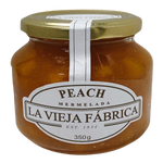 Glass jar of Fragata Peach Jam with a golden peach and jam spread visible, showcasing the fruity, sweet preserve.