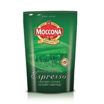 Moccona Espresso Instant Coffee drink in a glass mug with a frothy top and coffee beans in the background.