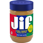 Jif Extra Crunchy Peanut Butter jar with textured nutty spread visible inside, on a grocery shelf.