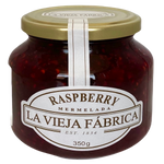 Jar of Fragata Raspberry Preserves with fresh raspberries, showcasing the vibrant red jam in a clear glass jar.