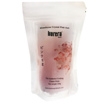 Kurera Himalayan Salt fine grain in a clear container, showing the pink, coarse-textured salt for culinary use.