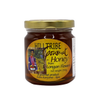 Jar of Hilltribe Longan Honey with a wooden honey dipper on a rustic wooden surface.