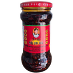 Bottle of Laoganma Fried Chilli in Oil sauce with red chili peppers and sesame seeds, ready to add spice to dishes.