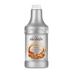 Monin caramel sauce in a 1.89L bottle, ideal for desserts and beverages, shown in a clear image of the product.